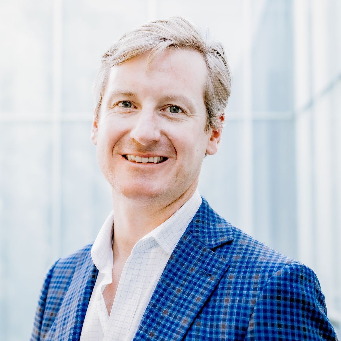 A man in a blue suit and white shirt is smiling for the camera.