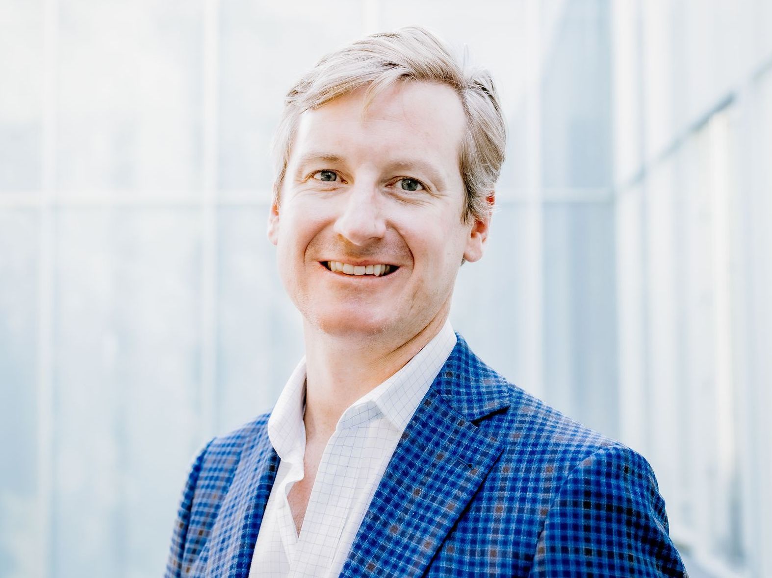 A man in a blue suit and white shirt is smiling for the camera.