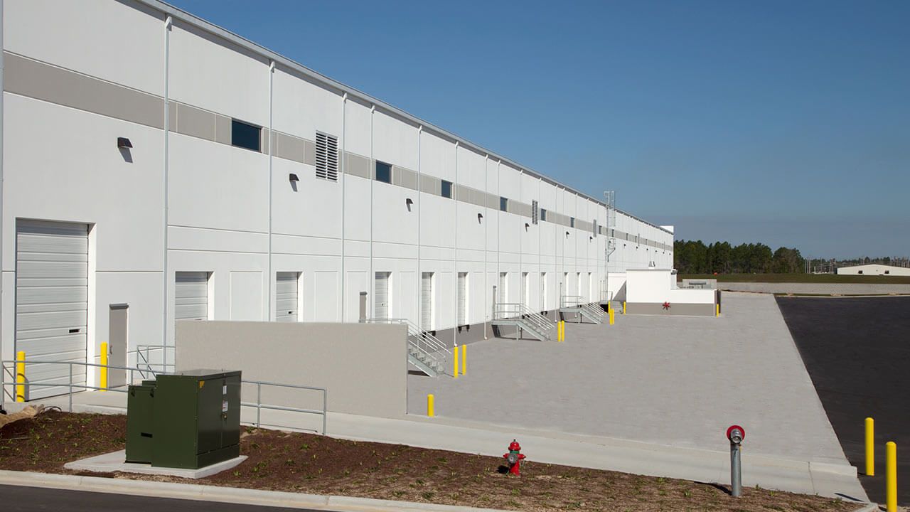 A large white building with a lot of doors and a fire hydrant in front of it.