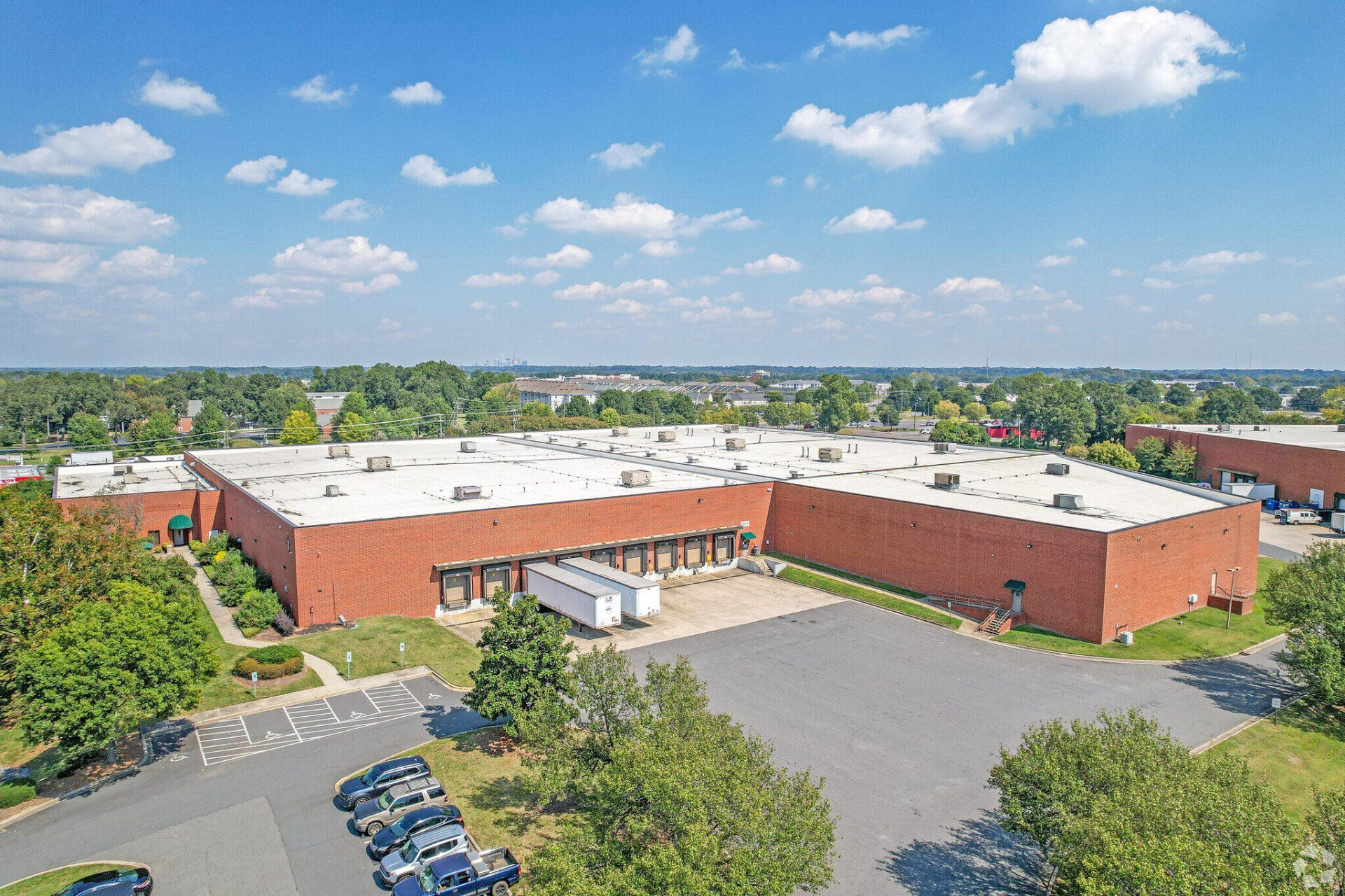 An aerial view of a large warehouse with a lot of cars parked in front of it.