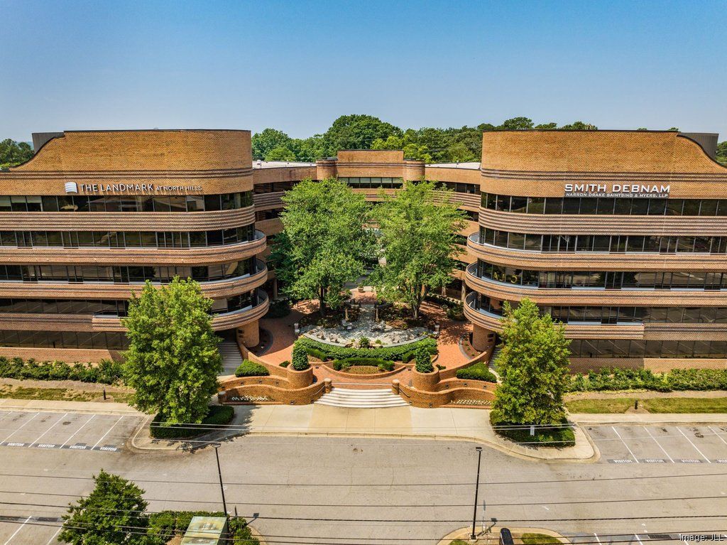 An aerial view of a large building with a lot of trees in front of it.