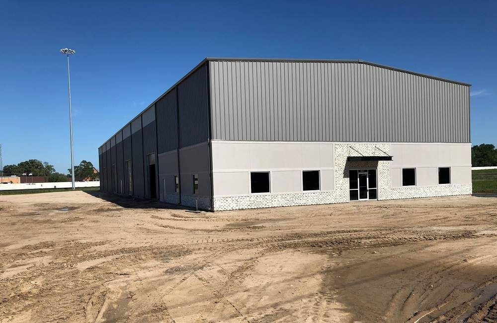 A large building is being built in a dirt field.