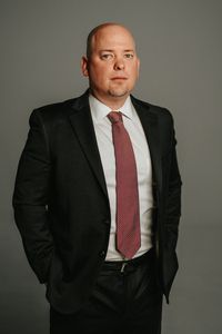 A man in a suit and tie is standing with his hands in his pockets.