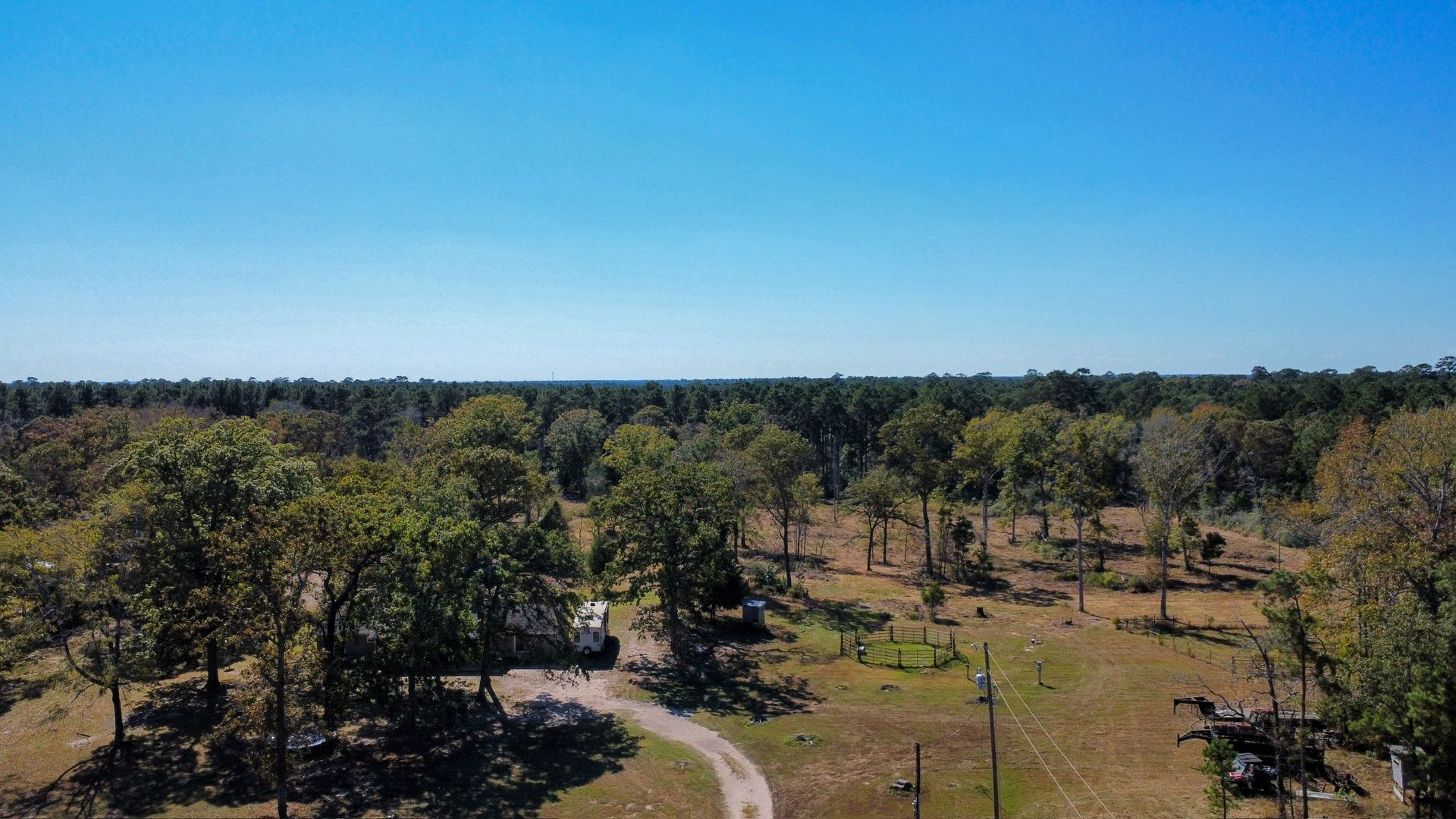 An aerial view of a house in the middle of a field surrounded by trees.