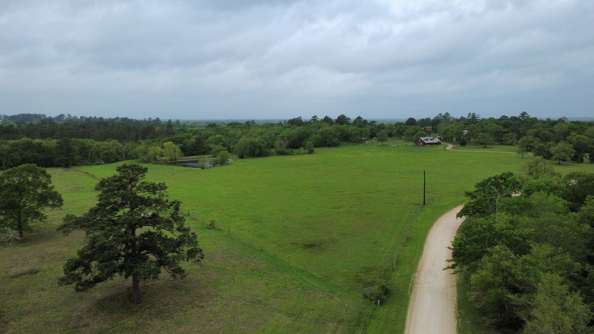 An aerial view of a dirt road going through a grassy field.