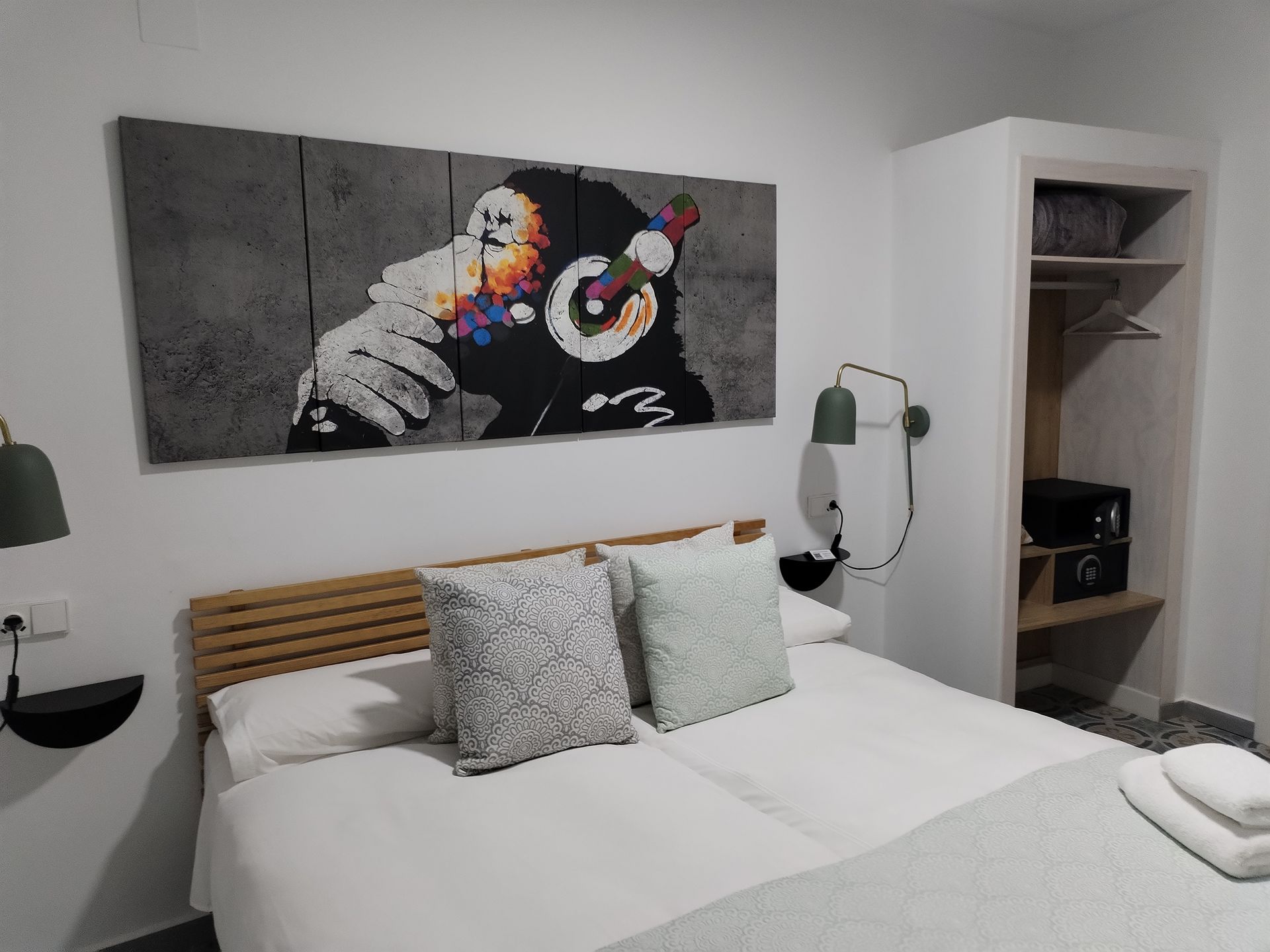 Dormitorio con arte de monos estilo Banksy, cama doble y armario abierto.