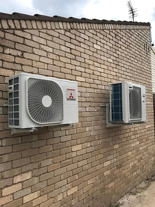 Two Air Conditioners are Mounted on a Brick Wall  — Priest Airconditioning in Ashmont, NSW