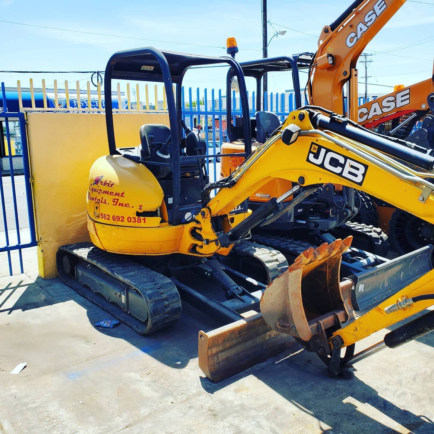 A yellow jcb excavator is parked next to a case excavator