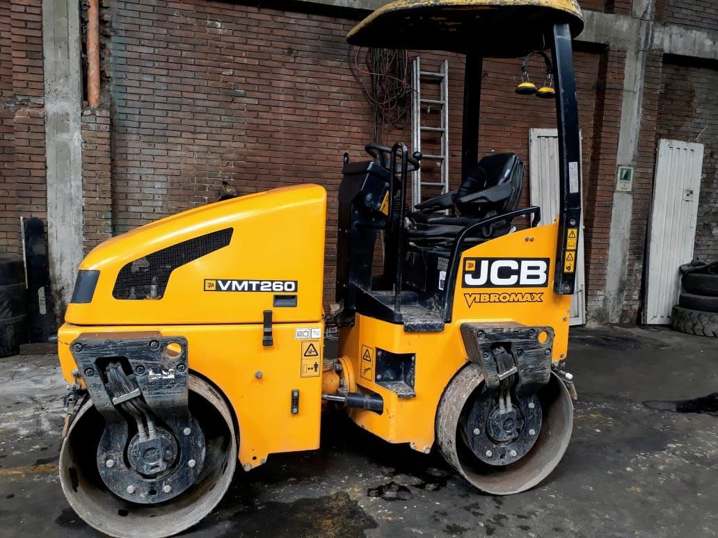 Un rodillo compactador JCB amarillo está estacionado en un estacionamiento.