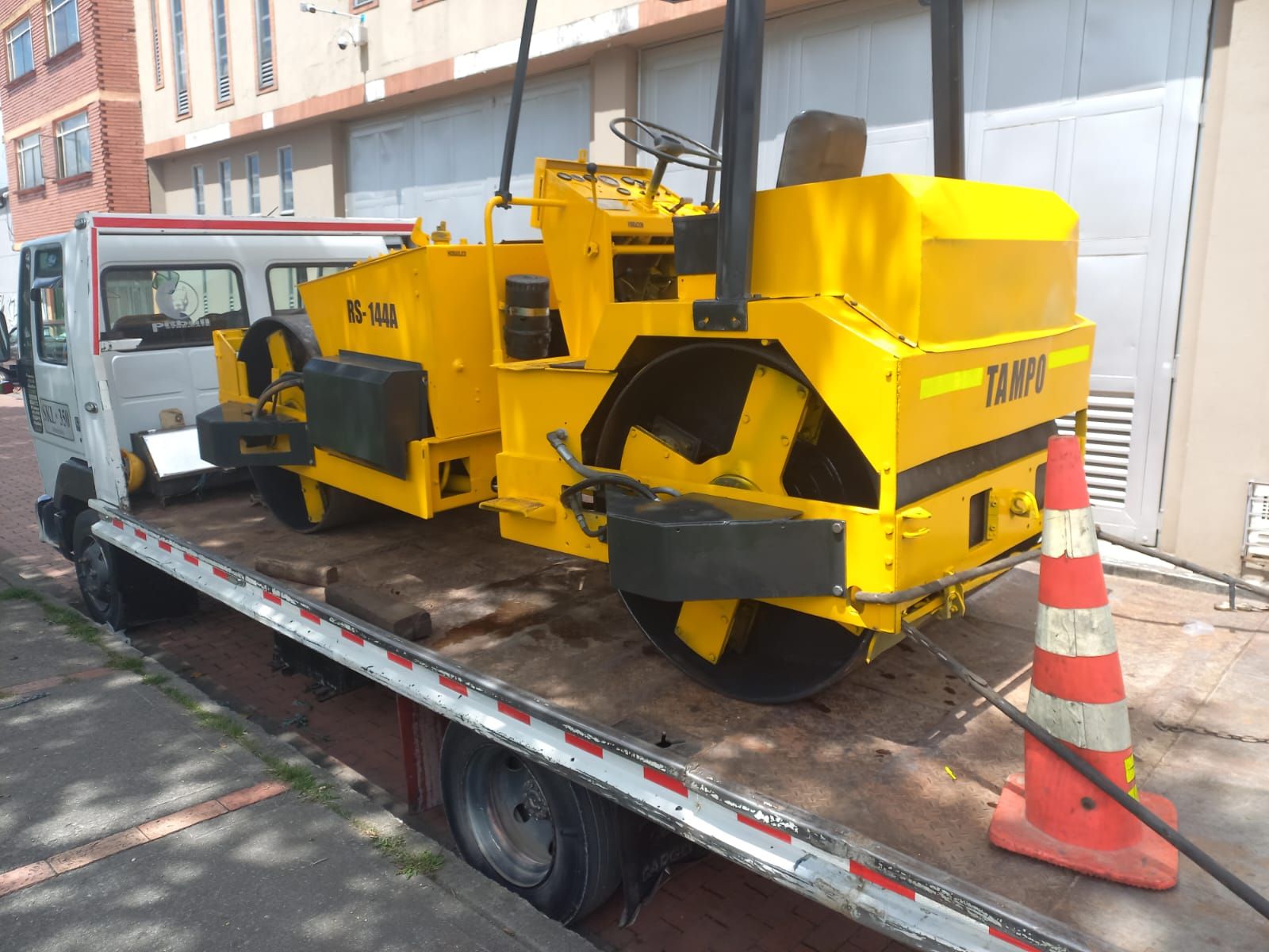 Una máquina amarilla está sentada encima de una grúa.