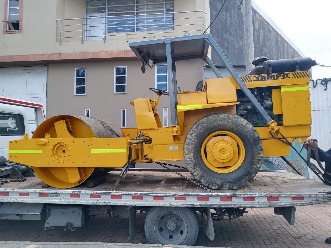 Un tractor amarillo está sentado encima de un camión de plataforma.