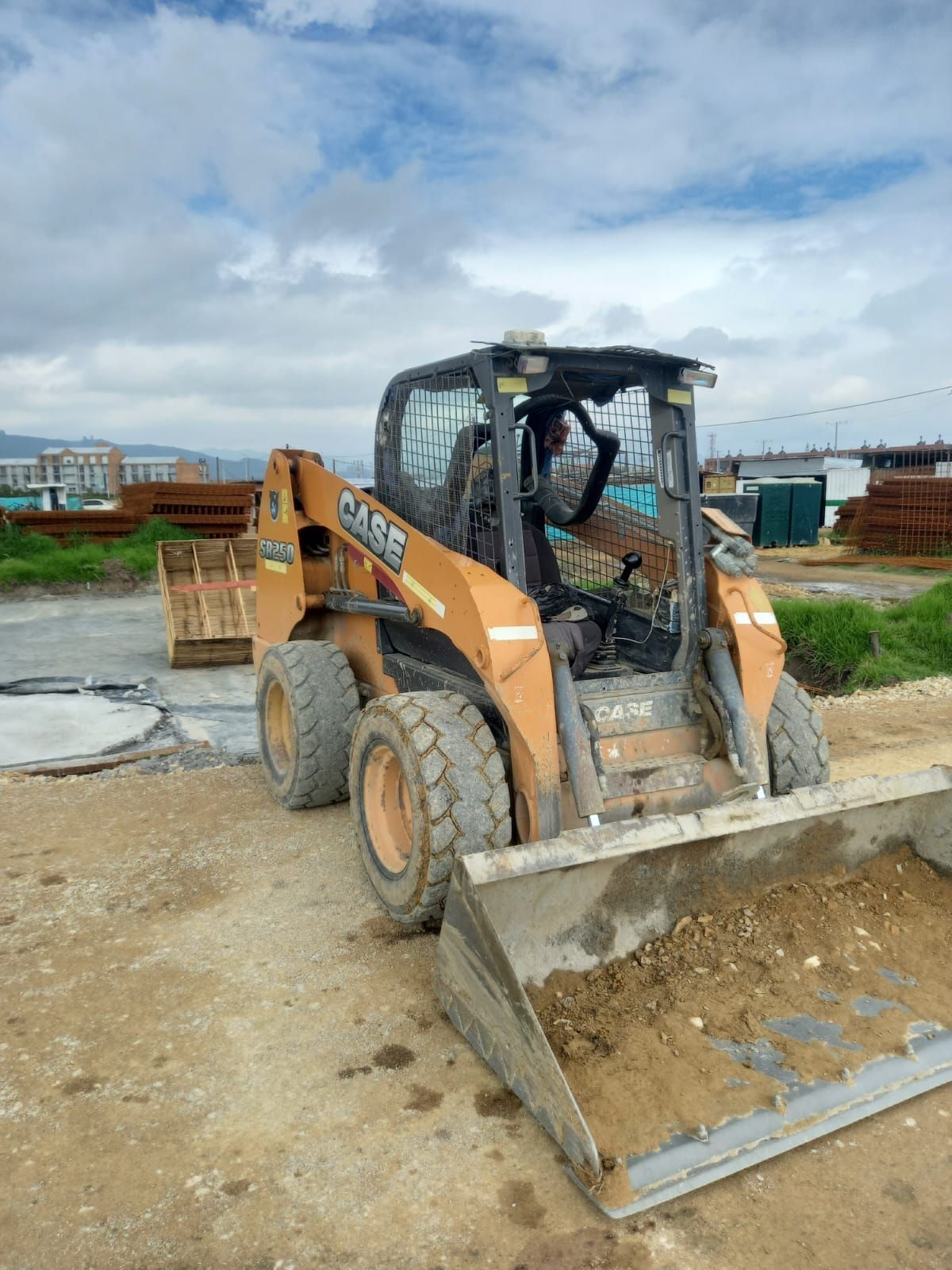 Un minicargador está estacionado en un campo de tierra.