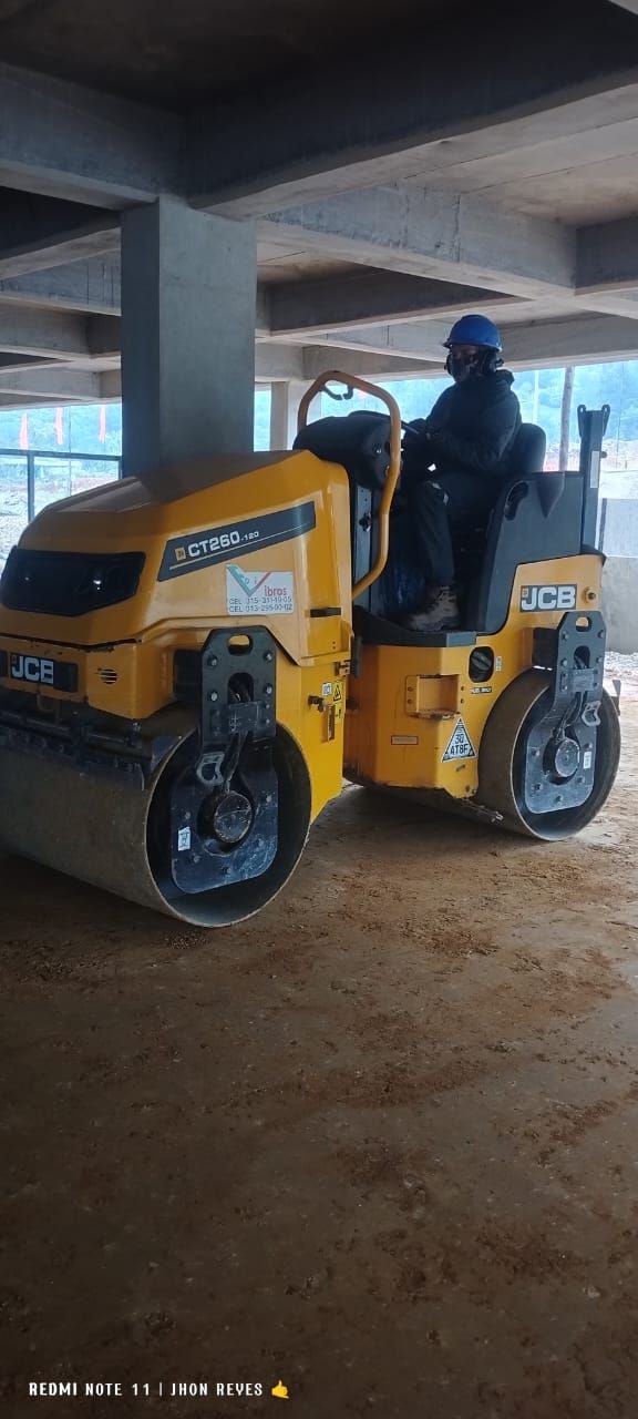 Un hombre conduce un rodillo amarillo en un edificio en construcción.