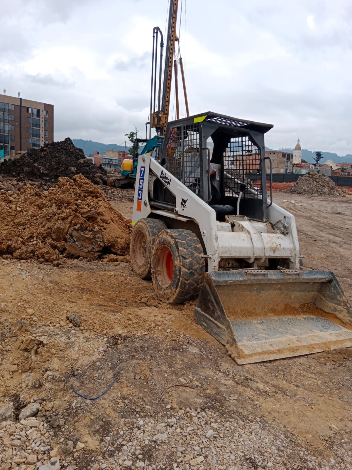 Una minicargadora Bobcat está estacionada en un campo de tierra.