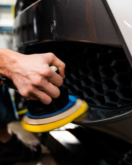 Person using a polisher on a car's bumper.