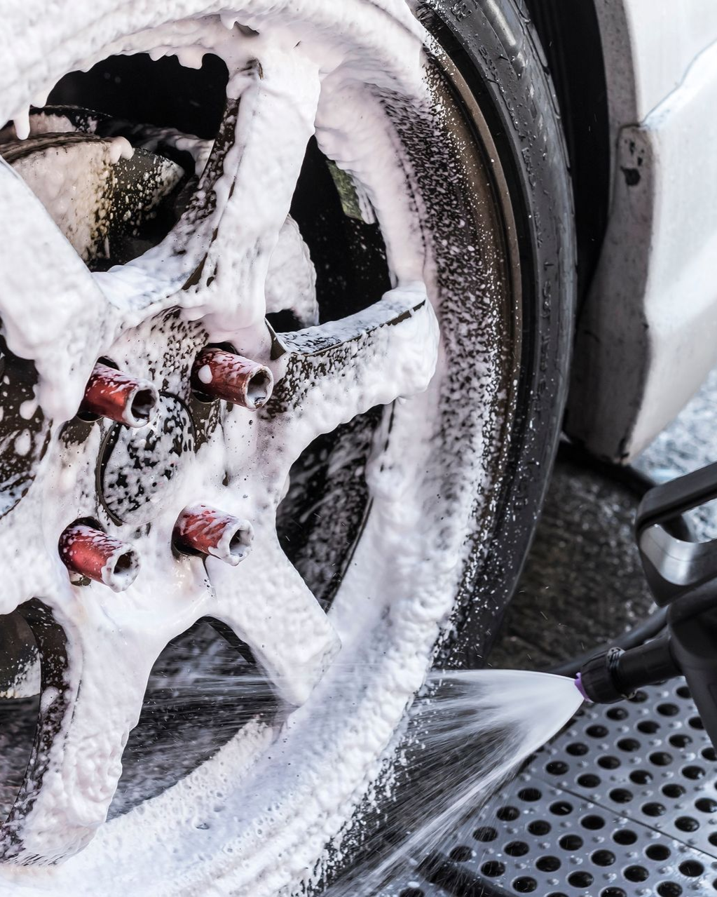 Car wheel being washed with foamy soap.