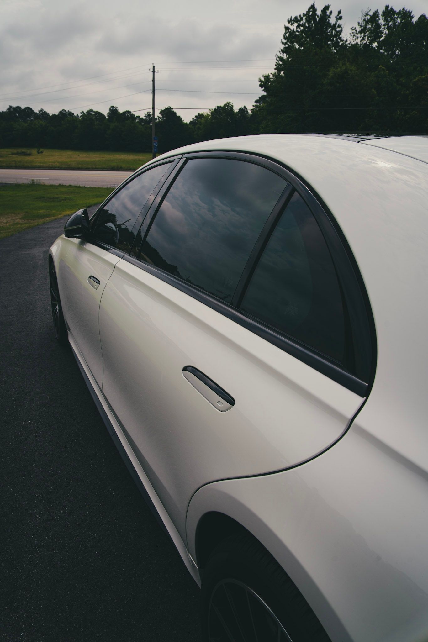 White sports car parked outdoors with trees in the background.