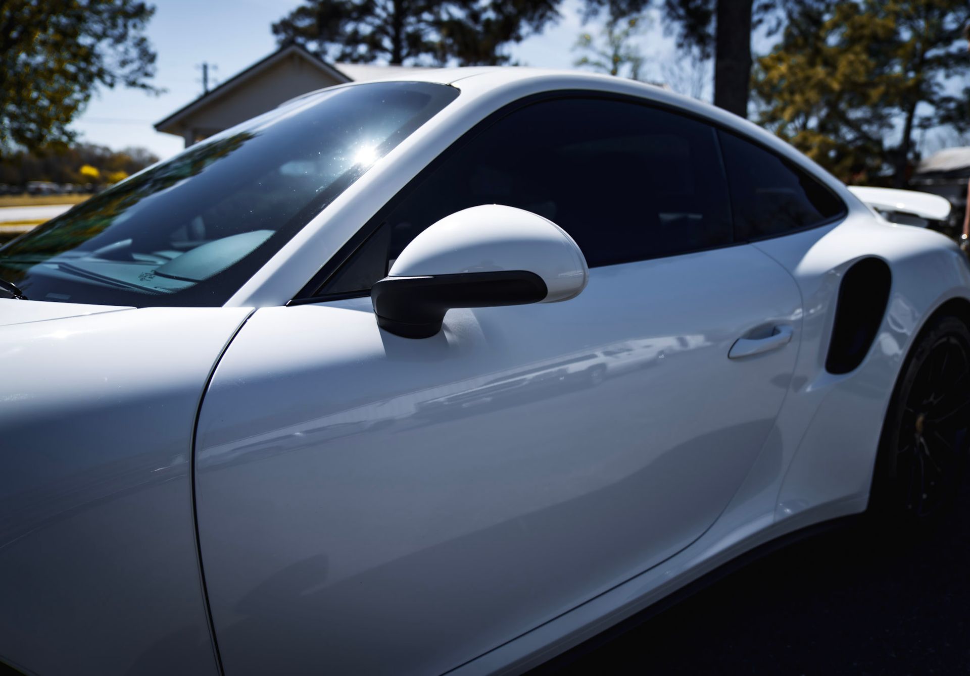 White and blue Dodge Challenger with open door in a garage.