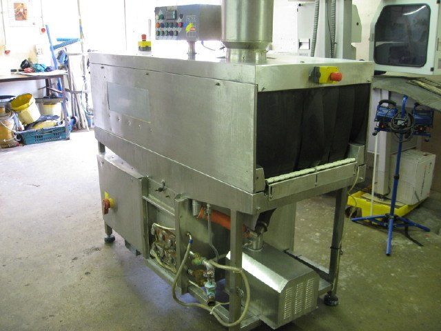 Stainless steel industrial machine with conveyor belt, red emergency stop button, in a workshop.