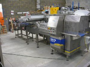 Industrial food processing machine, DELTA model, stainless steel, in a factory setting.