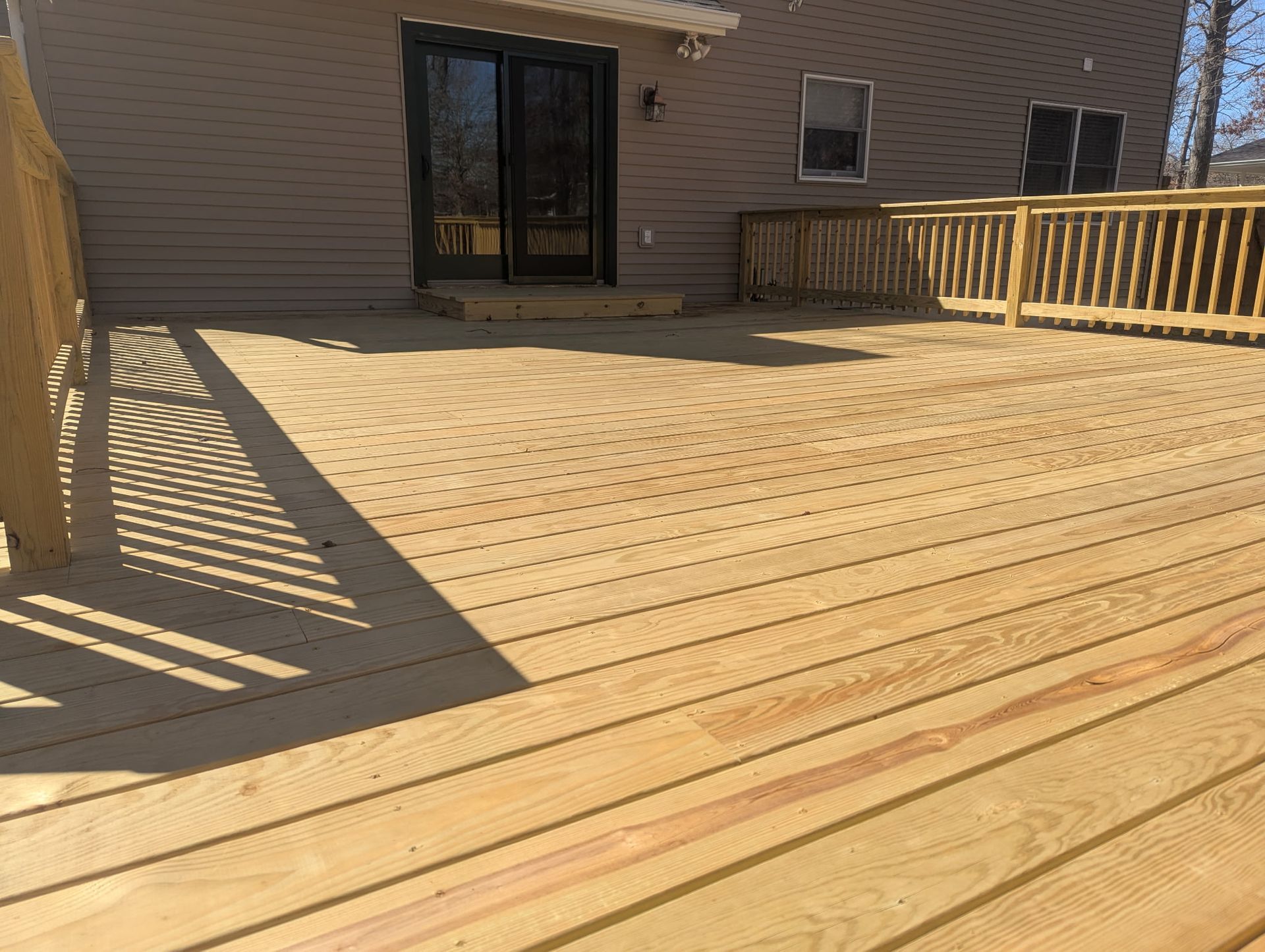 A wooden deck with a railing in front of a house.