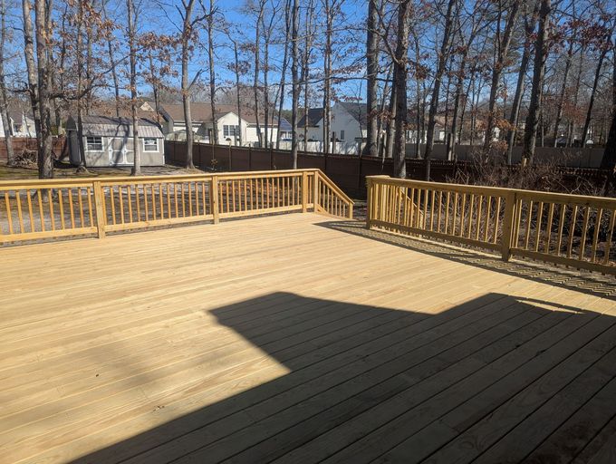 A large wooden deck with a wooden railing and stairs