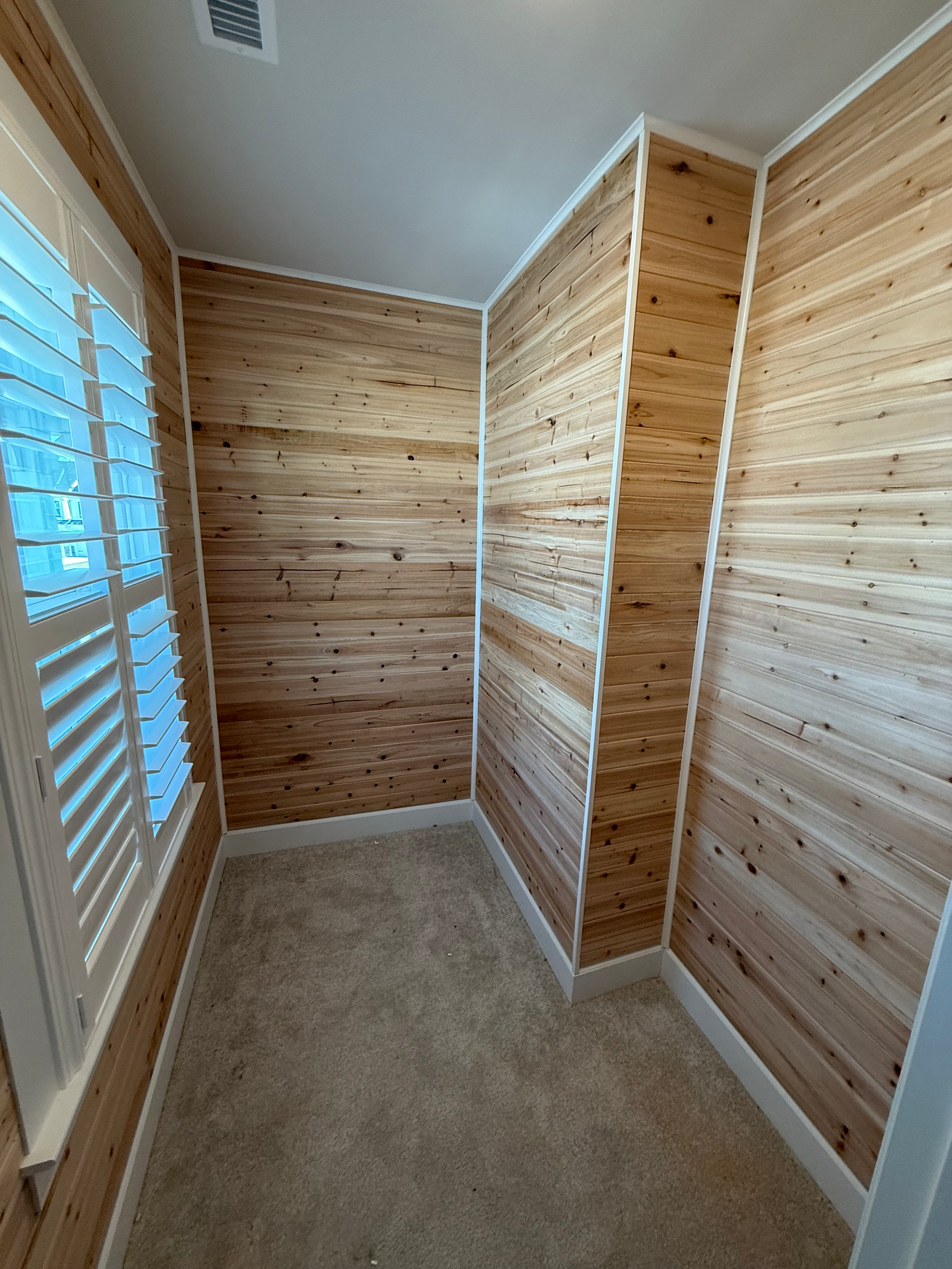 A room with wood paneling and shutters on the windows.