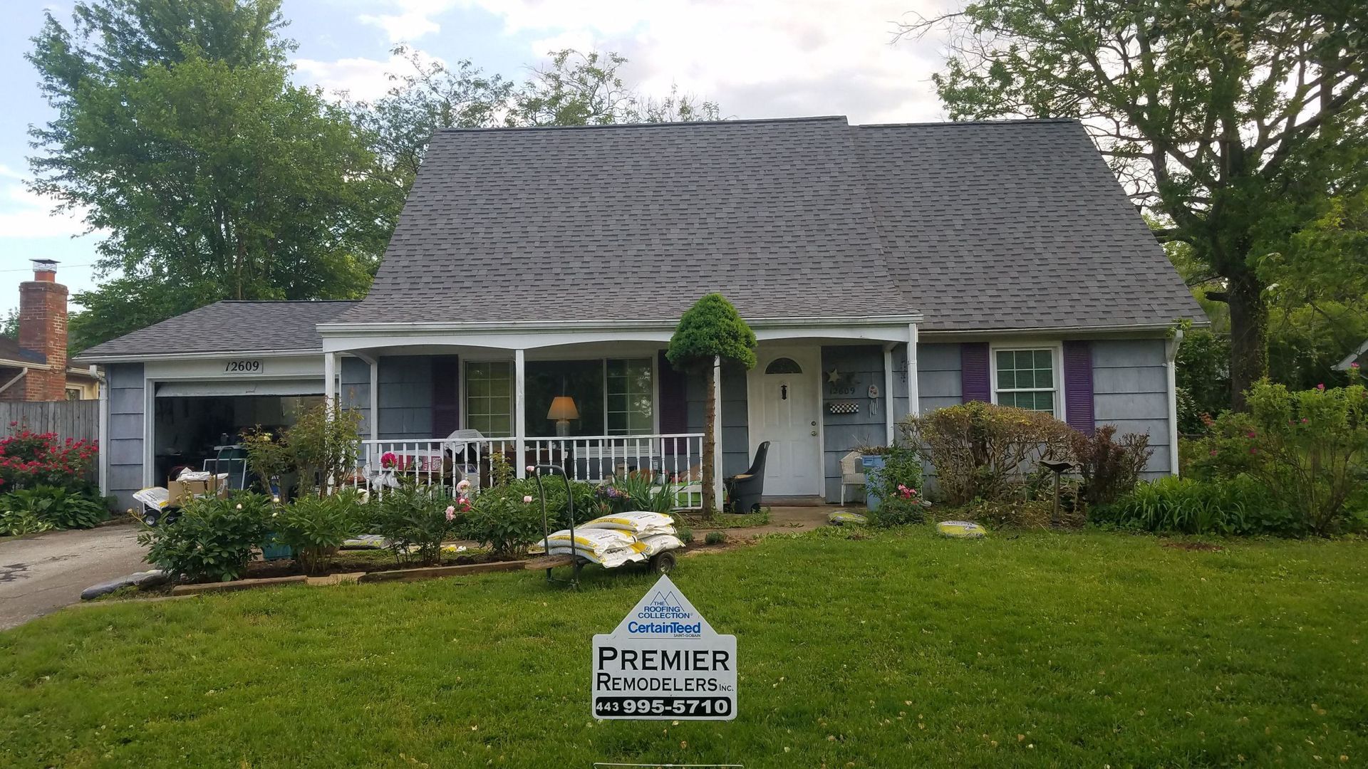 A house with a gray roof and purple shutters is for sale.