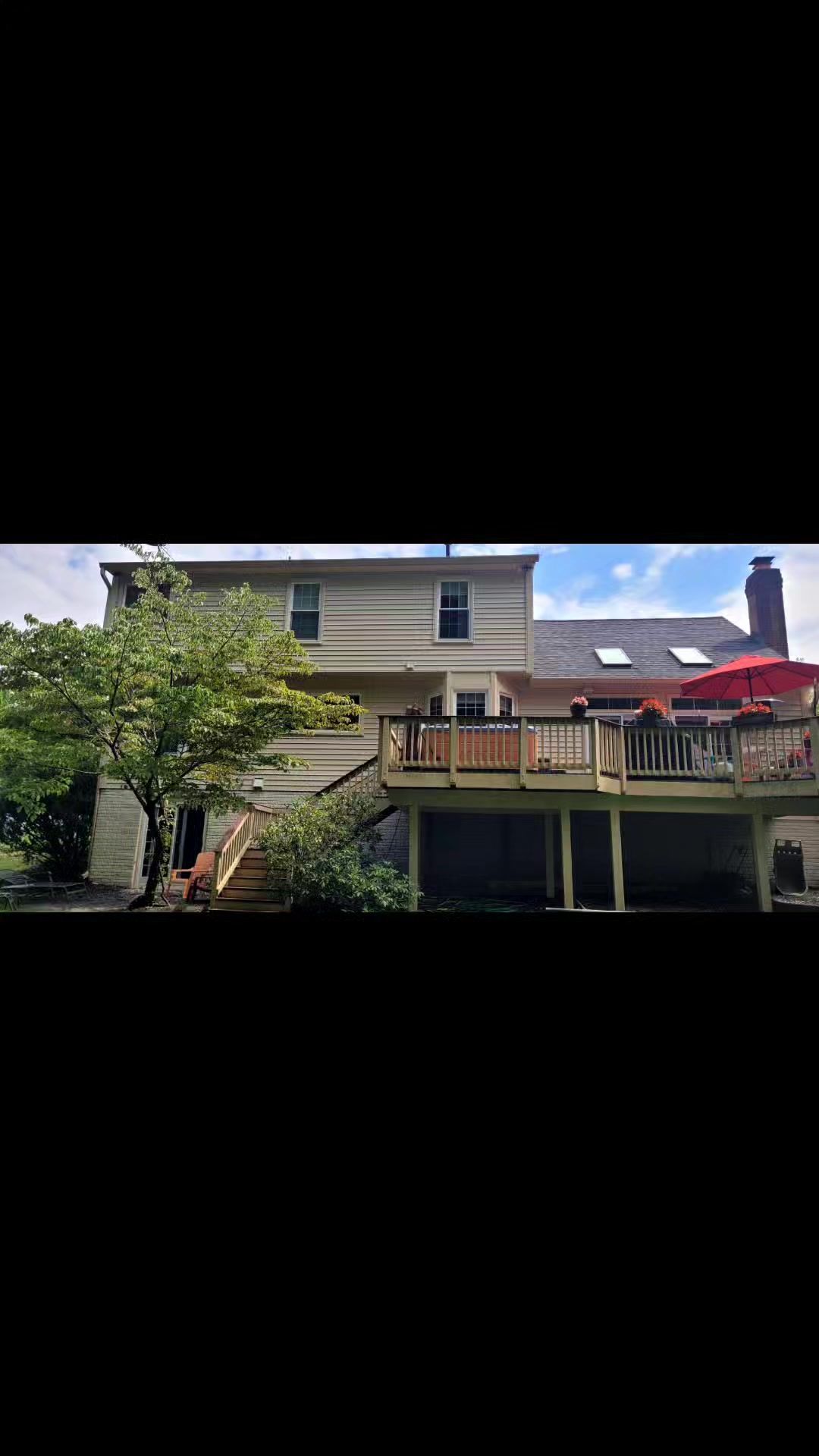 The back of a house with a large deck and stairs.