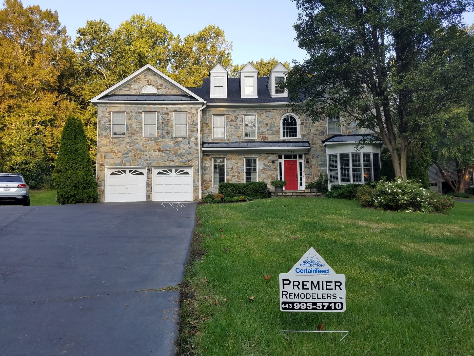 A large stone house with a for sale sign in front of it.