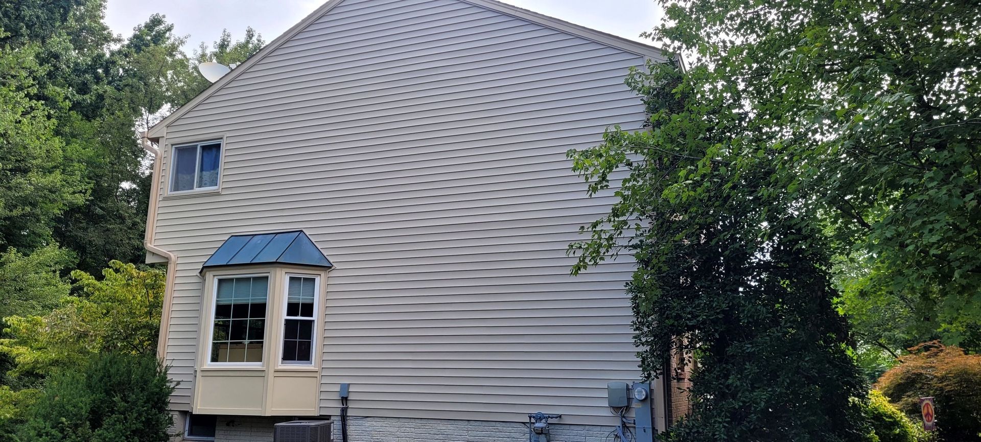 A large white house with a blue roof is surrounded by trees.