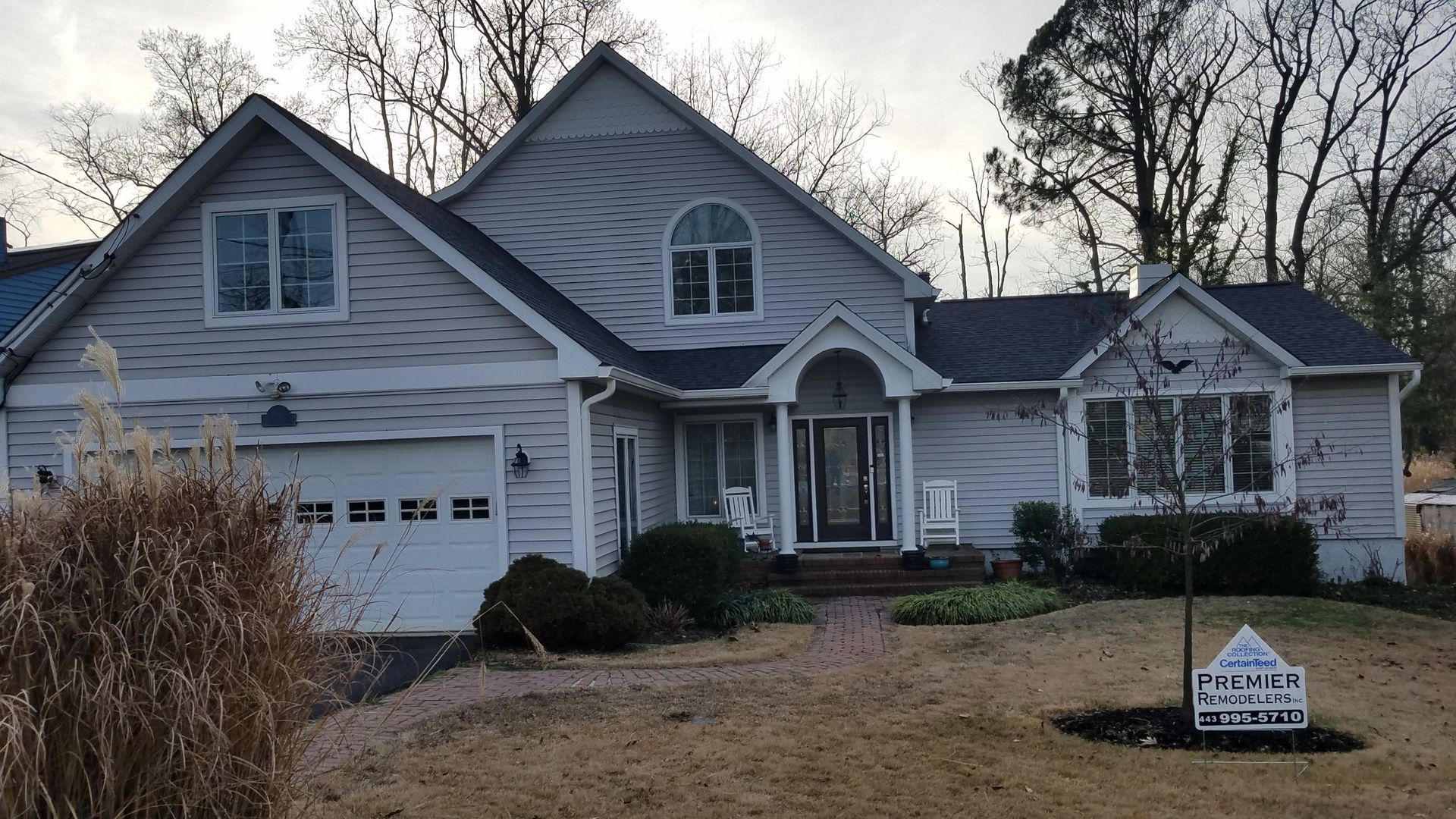 A large white house with a blue roof is for sale