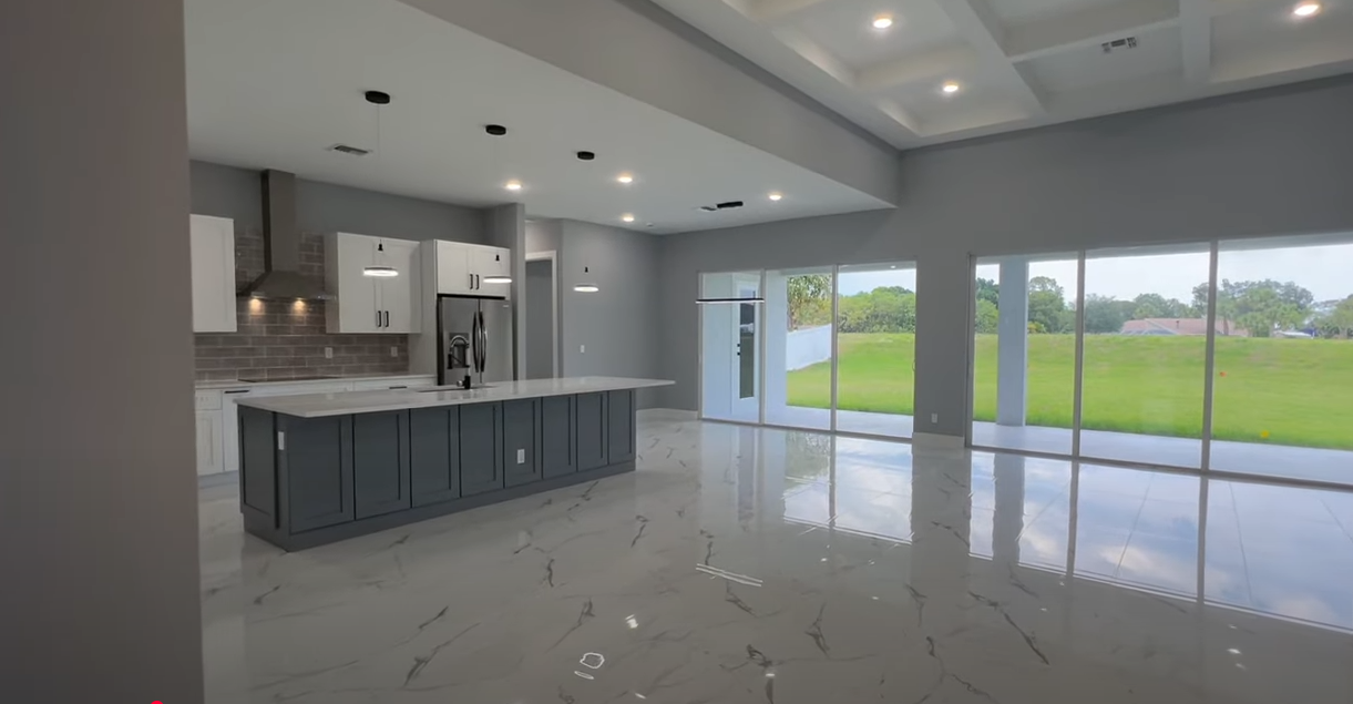 Stone tile in a large kitchen with large windows looking out into a grassy green backyard