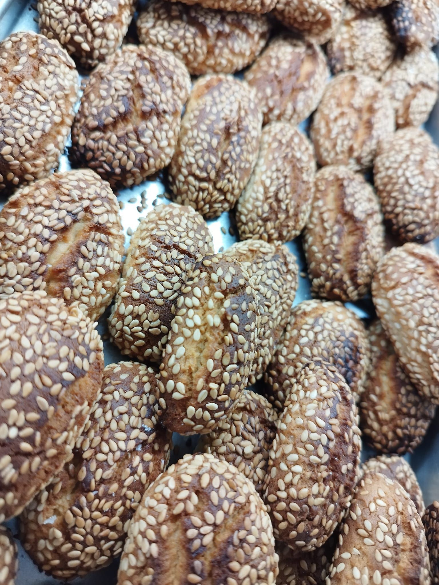 Un mucchio di biscotti ai semi di sesamo sono appoggiati uno sopra l'altro su un tavolo.