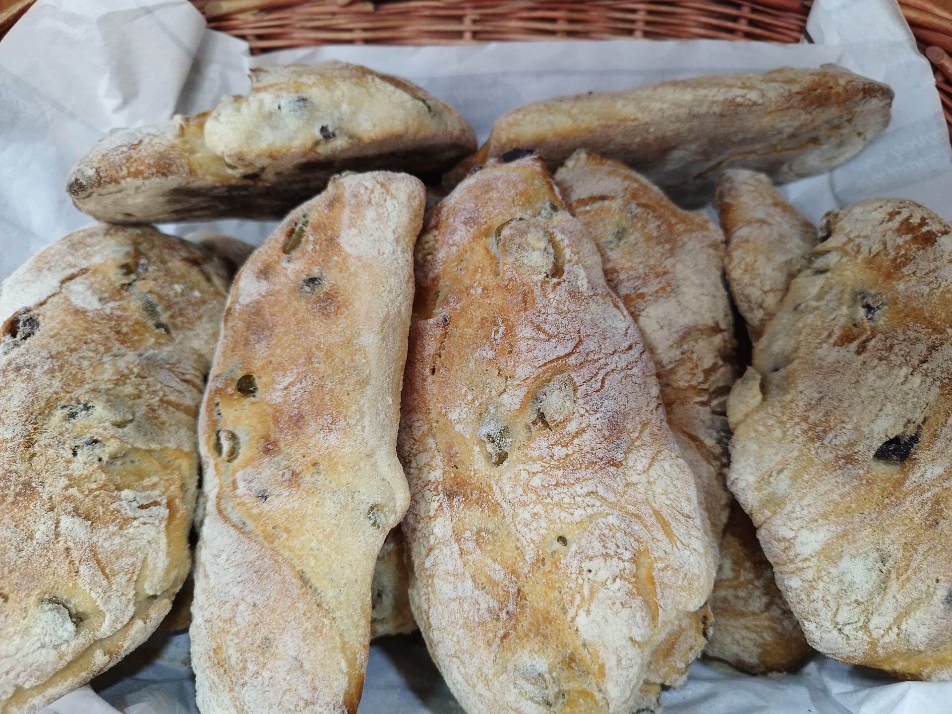 Un cestino pieno di pane è appoggiato su un tavolo.