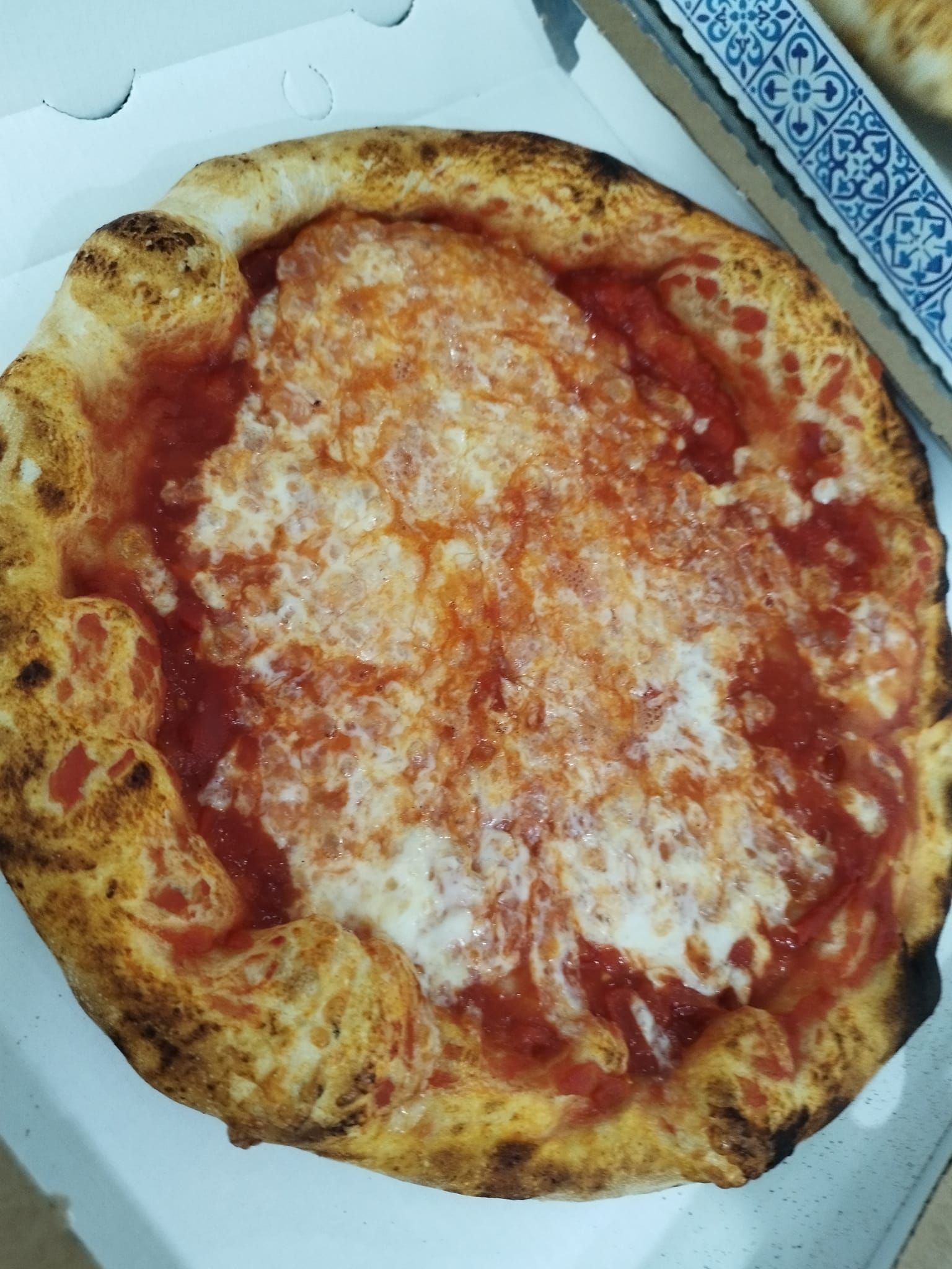 Una pizza con salsa di pomodoro e formaggio è in una scatola.