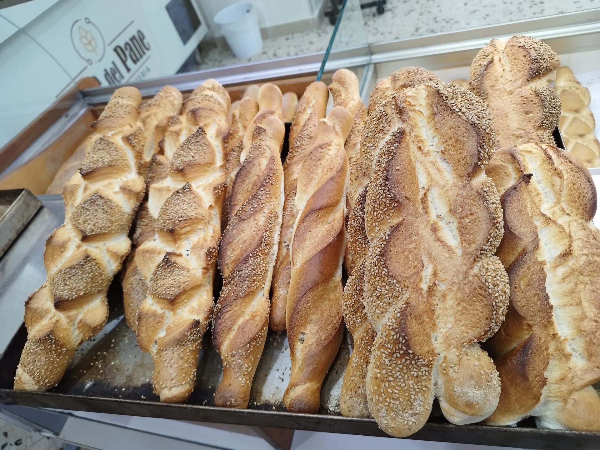 In una panetteria ci sono diverse pagnotte di pane su un vassoio.