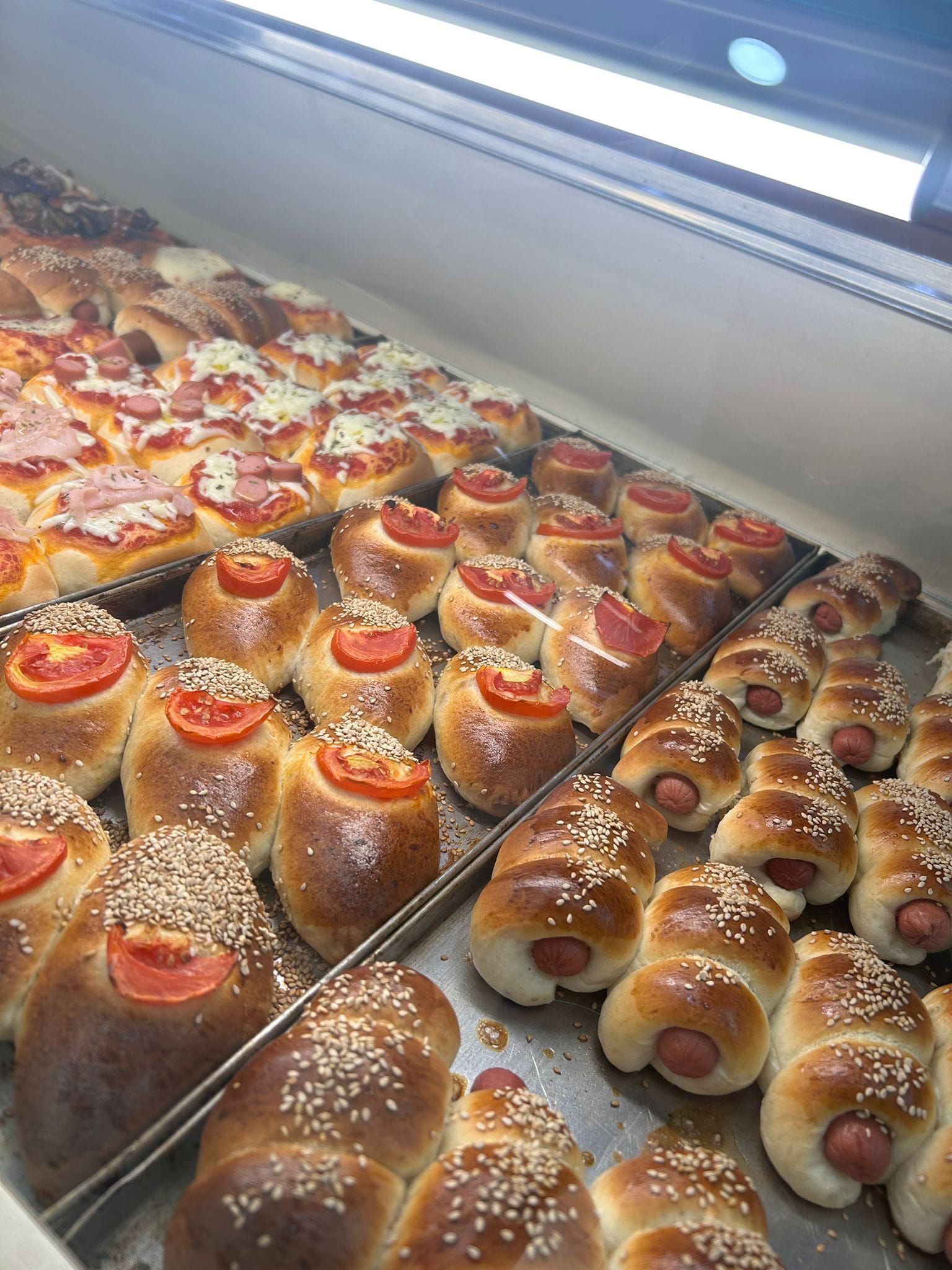 Un mucchio di hot dog sono appoggiati su un vassoio in una panetteria.