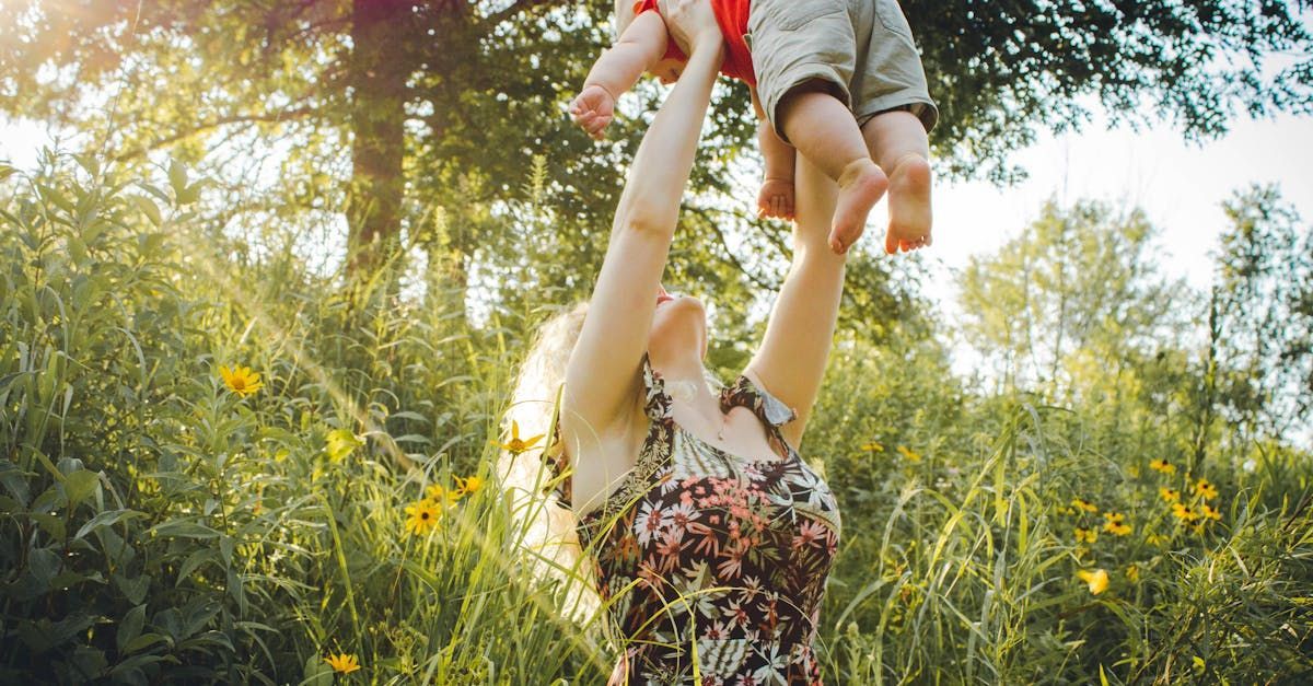 A woman is holding a baby in her arms in front of a window.