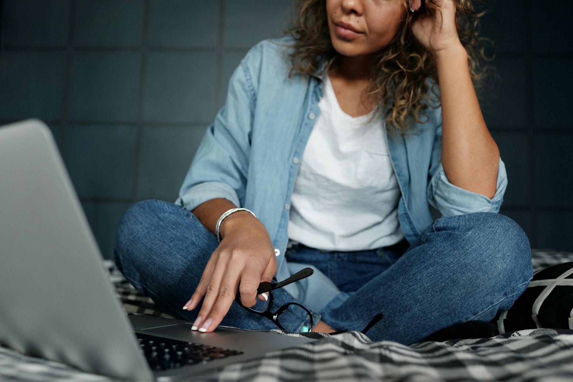 A woman is sitting on a bed using a laptop computer.