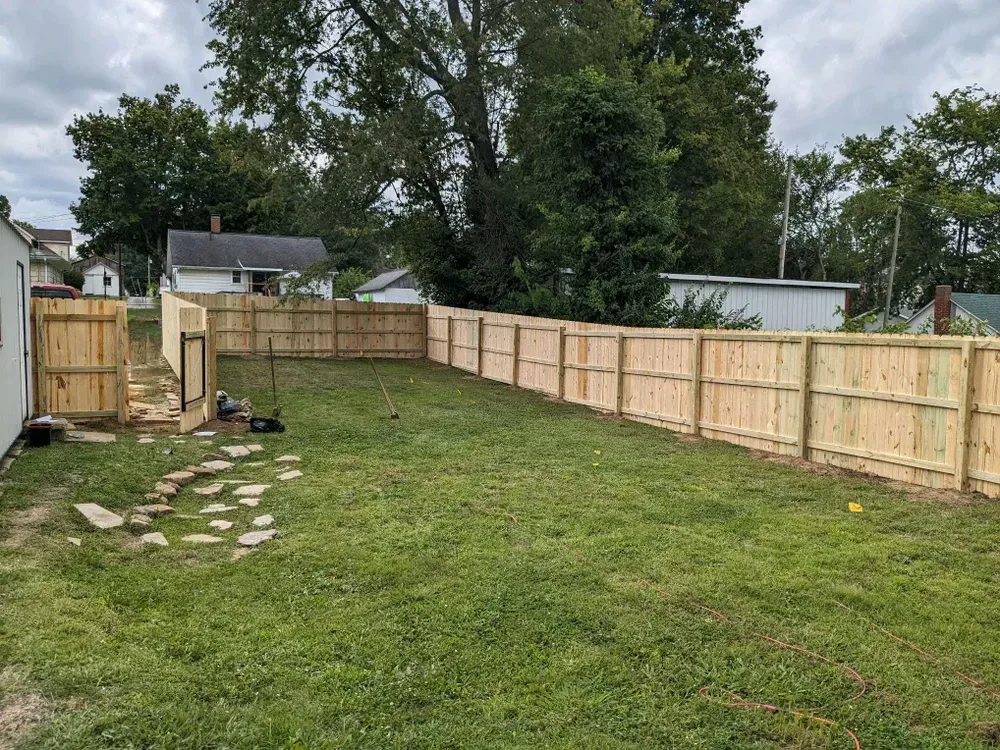 A wooden fence is being built in the backyard of a house.