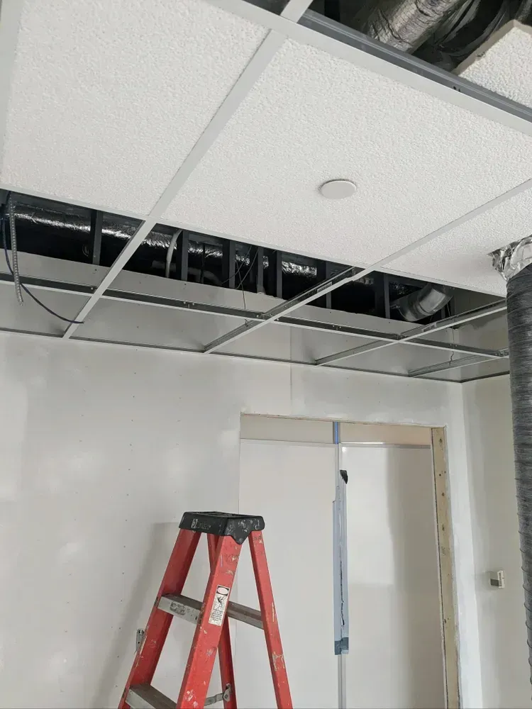 A red ladder is sitting under a ceiling that is being remodeled