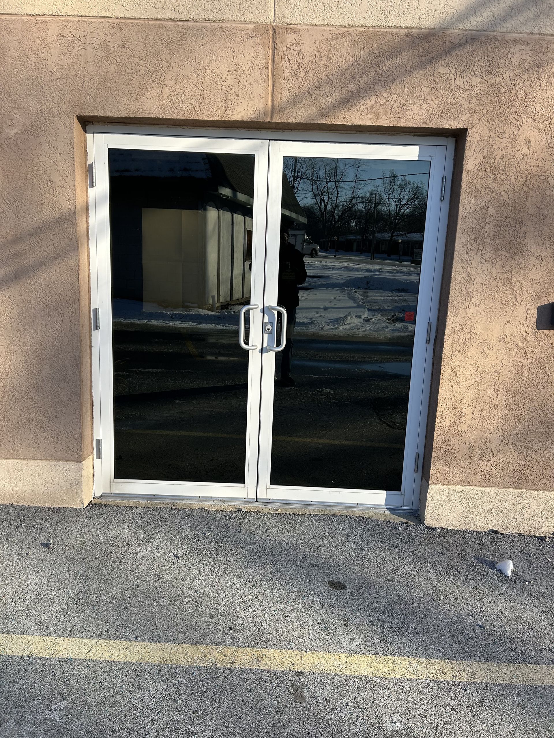 A building with a double glass door and a parking lot in front of it