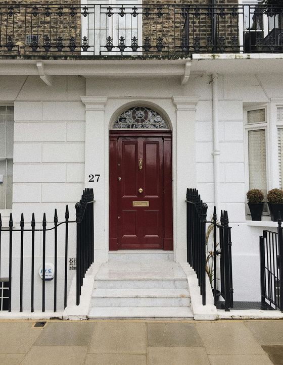 A white house with a red door and the number 27 on it