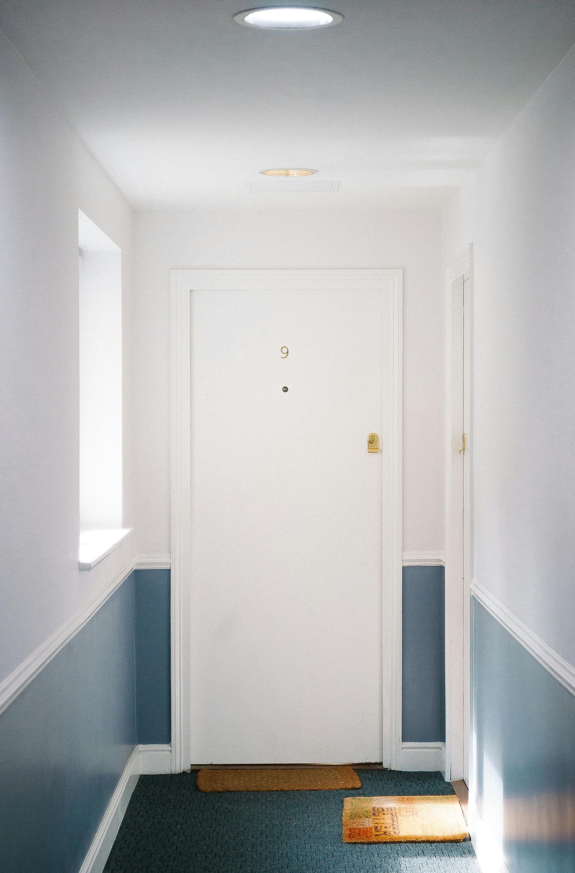 A hallway with a white door and blue walls