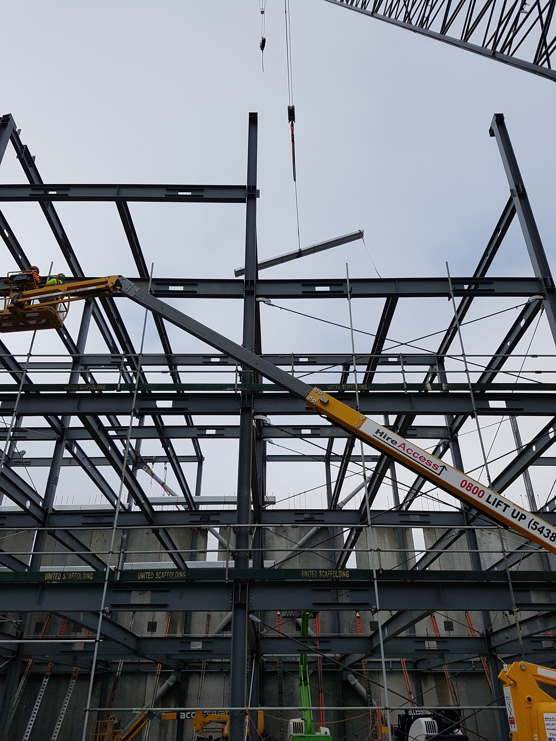 A large metal structure is being built with a crane in the background.