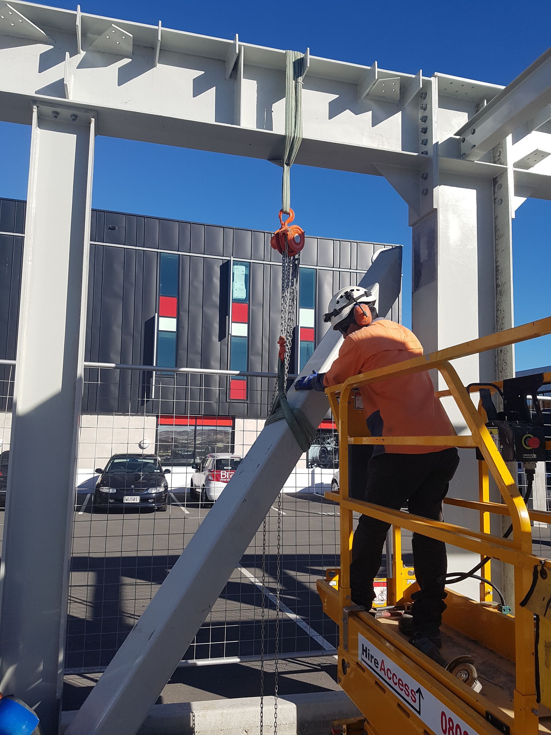 A construction worker is standing on a platform with a crane in the background