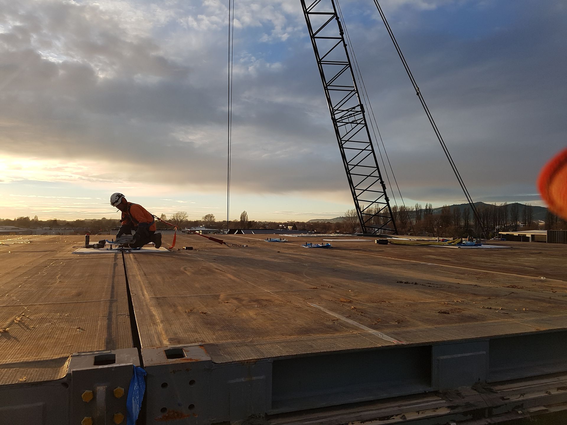 A man is working on a bridge with a crane in the background.