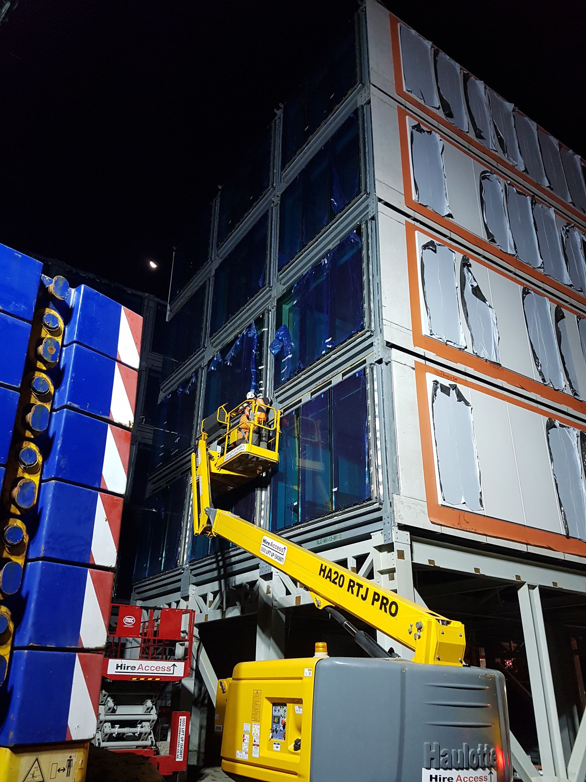 A crane is cleaning the windows of a building at night.