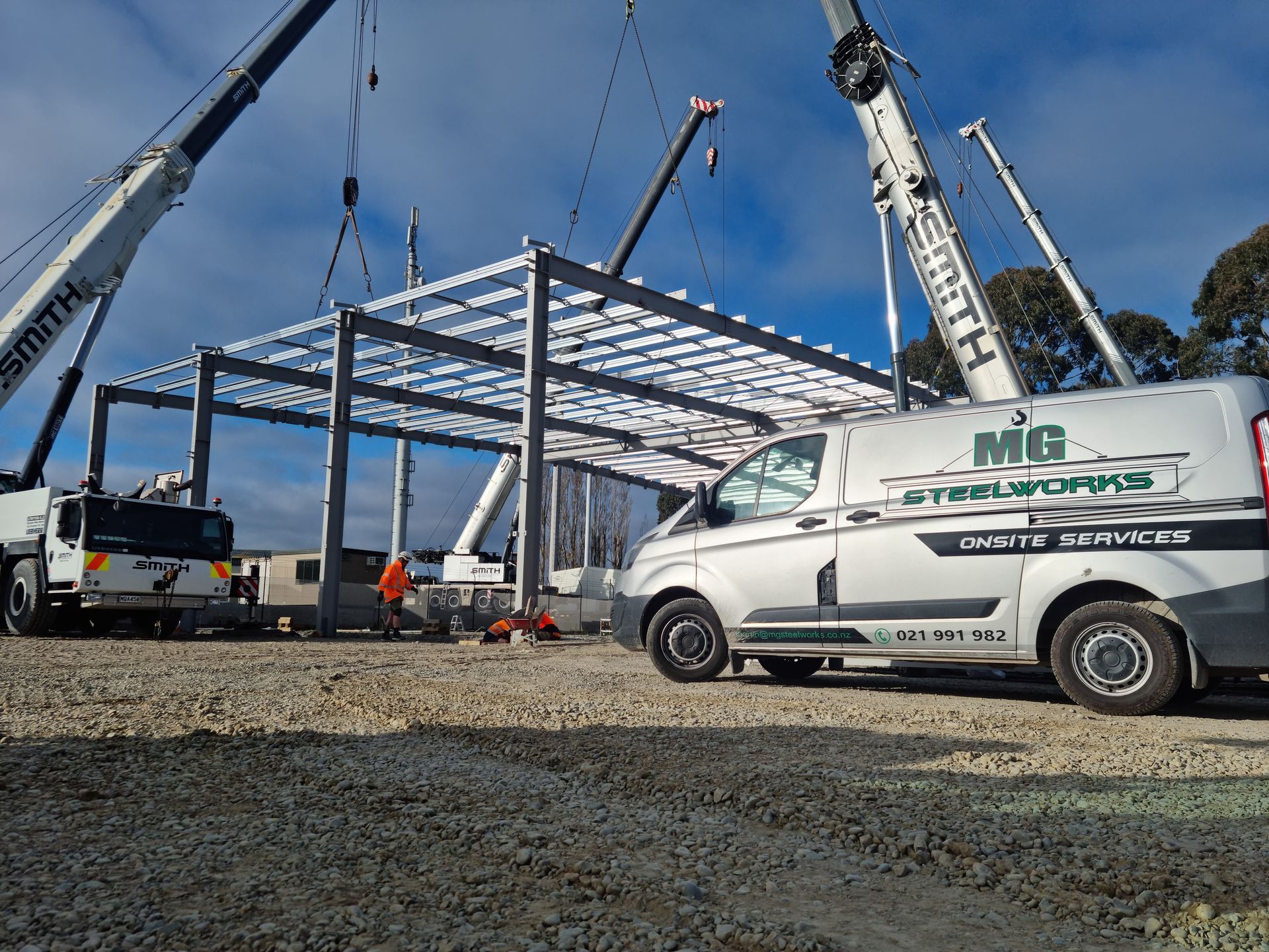 A white van is parked in front of a building under construction